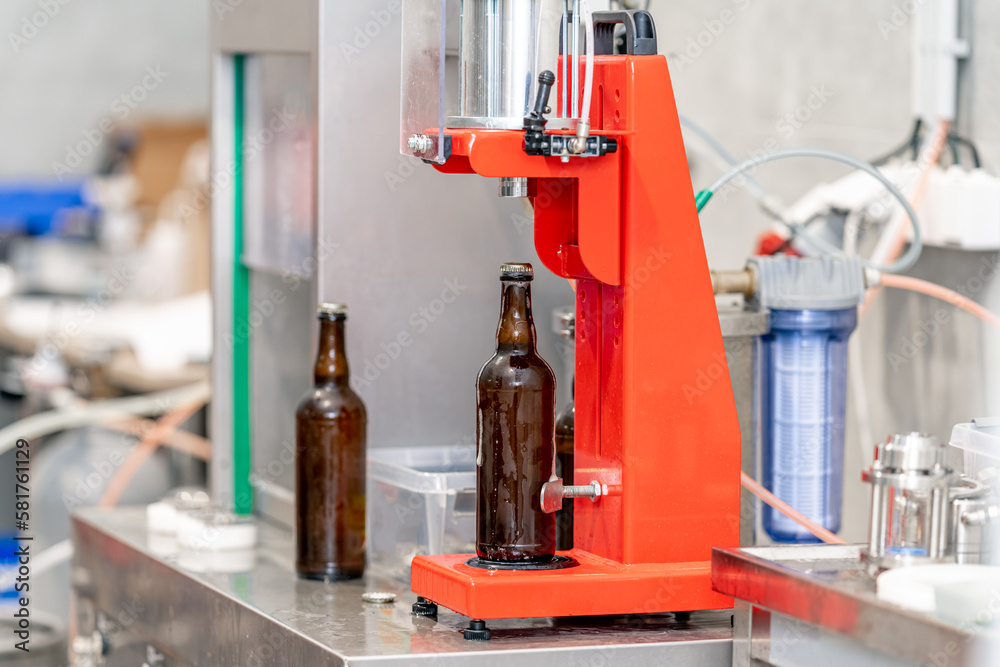 capping beer bottles on a machine in a brewery capping beer bottles on a machine in a brewery