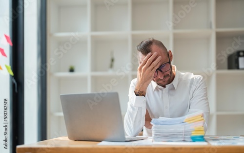 businessmen are worried about the work and the economic downturn. Tired and worried business man at workplace in office holding his head on hands