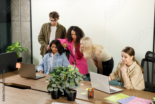Feeling shock. Surprised worried young coworkers are looking at screen of laptops while keeping eyes wide opened and expressing consternation because of unexpected big mistake in their project
