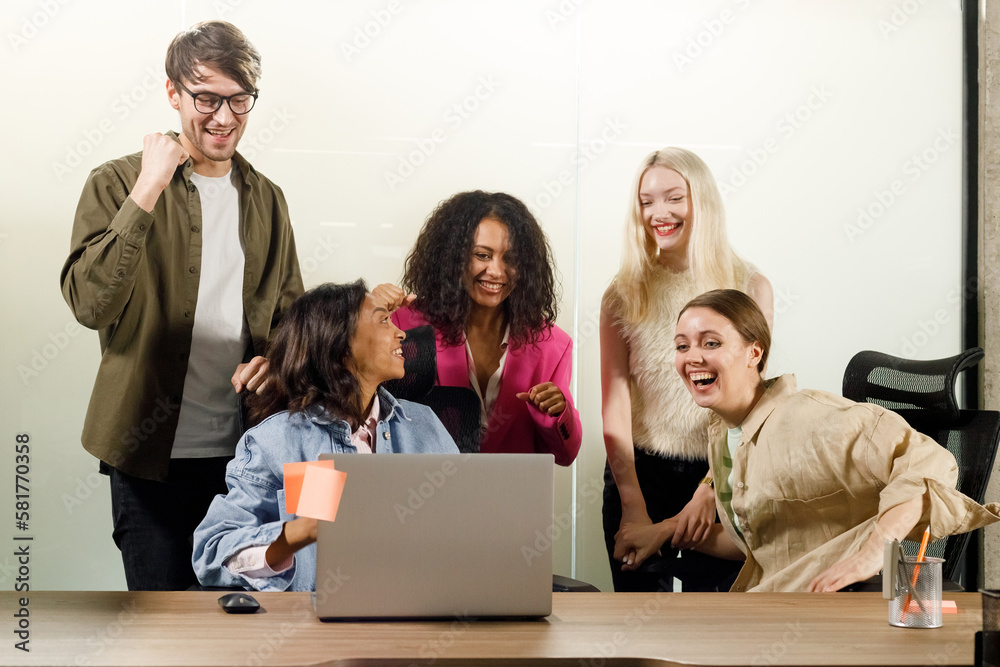 Young people working at the office with laptop screaming proud, celebrating victory and success very excited with raised arm Young people working at the office with laptop screaming proud, celebrating victory and success very excited with raised arm