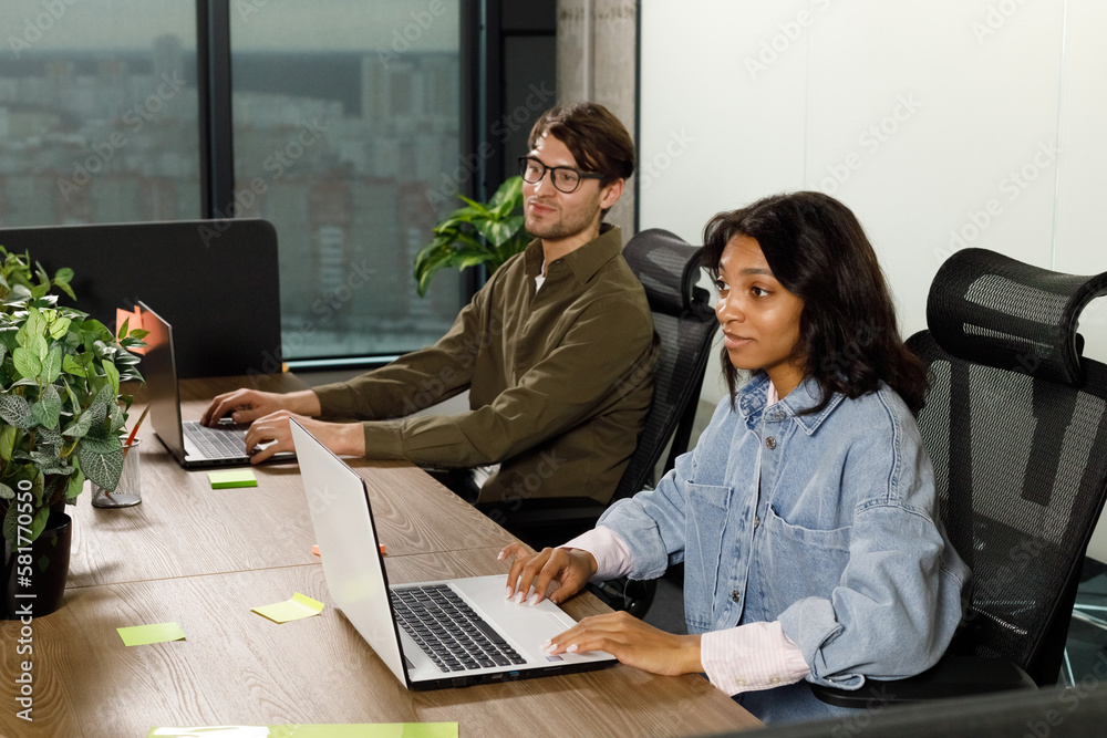 Two business workers smiling happy working sitting on desk at the office Two business workers smiling happy working sitting on desk at the office