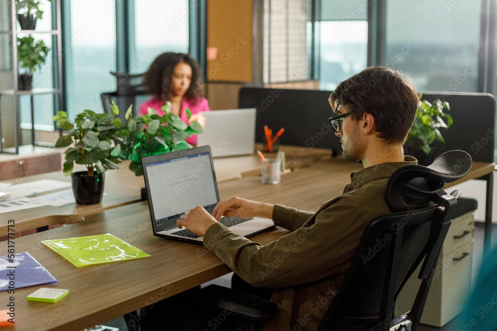 serious employees in casual clothes are sitting in a stylish modern office at laptops serious employees in casual clothes are sitting in a stylish modern office at laptops