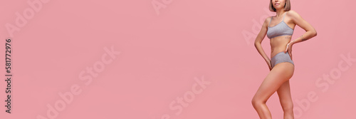 Portrait of young thin sportive woman in grey cotton inner wear posing over pink background. Concept of natural beauty, body and skin care, healthy eating
