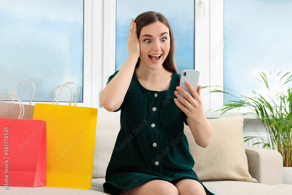 Special Promotion. Emotional young woman looking at smartphone on sofa indoors Special Promotion. Emotional young woman looking at smartphone on sofa indoors