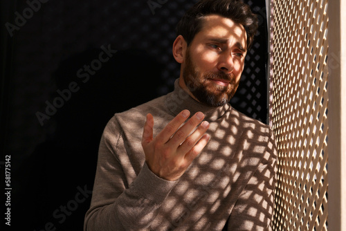 Upset man talking to priest during confession in booth photo