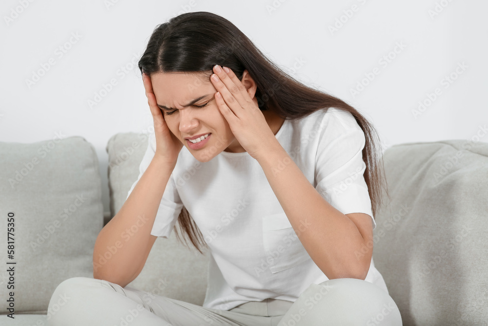 Young woman suffering from headache on sofa indoors. Hormonal disorders Young woman suffering from headache on sofa indoors. Hormonal disorders
