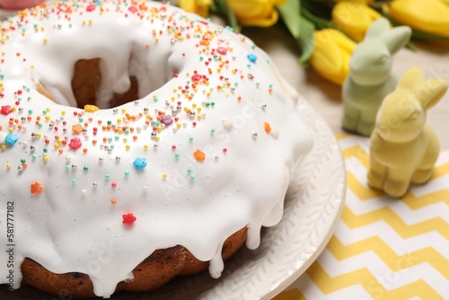 Fototapeta Naklejka Na Ścianę i Meble -  Easter cake with sprinkles, decorative bunnies and tulips on wooden table