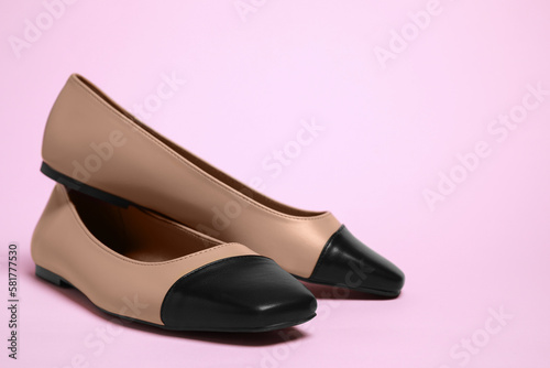 Pair of new stylish square toe ballet flats on pale pink background