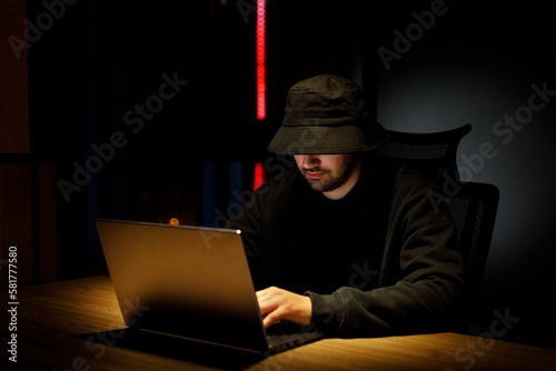 Overhead hacker working at computer and mobile phone typing text in dark room, An anonymous hacker uses malware with mobile phone to hack password, personal data steals money from bank
