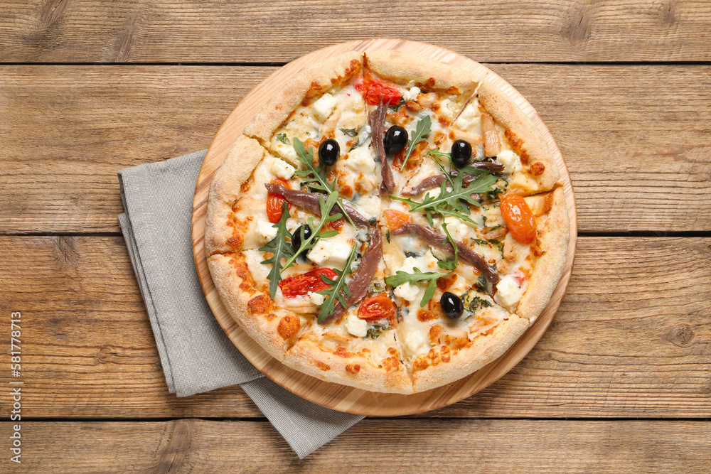 Tasty pizza with anchovies, arugula and olives on wooden table, top view