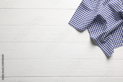 Blue checkered tablecloth on wooden table, top view. Space for text
