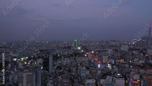 Wallpaper Mural Ho Chi Minh City, Vietnam evening featuring canal, landmark building and view over rooftops to urban sprawl and main road under lights. Aerial crane shot Torontodigital.ca