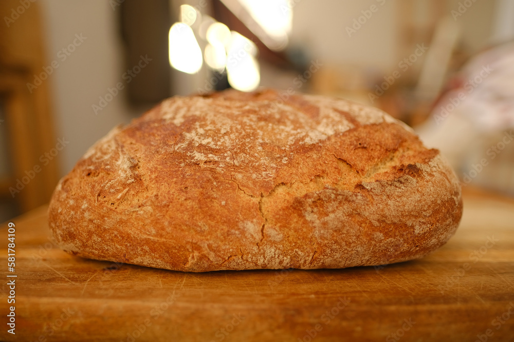 Big round appetizing fresh wholemeal bread with bran on wooden board, wheat, rye, multigrain bread, illuminated rays sun, concept bakery pastries, gluten products, diet, wholesome food, healthy eating