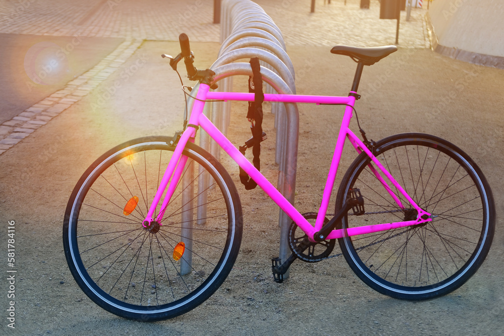 bright pink classic bicycle in urban landscape sunset parked in bike parking lot, vintage filter style, punctured wheel problem, vehicles in city, public bike rental, saddle sharing, property theft