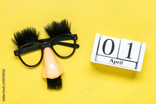 funny face - fake eyeglasses, nose and mustache, calendar with date 01 April on yellow background Happy fools day concept 1st April party Holiday greetind card