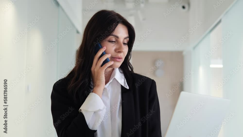 Businesswoman multitasks in the office, typing on a laptop and talking on the phone with a client. Her efficient use of technology and time management skills demonstrate dedication to work. Businesswoman multitasks in the office, typing on a laptop and talking on the phone with a client. Her efficient use of technology and time management skills demonstrate dedication to work.