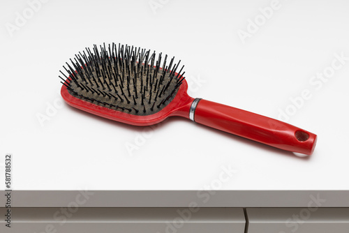 old red hairbrush with sticking out hair.