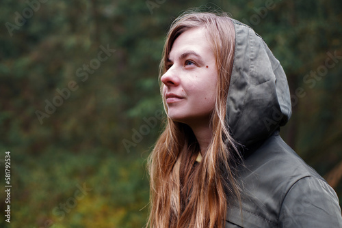 portrait of a woman in a raincoat looking away on a green background