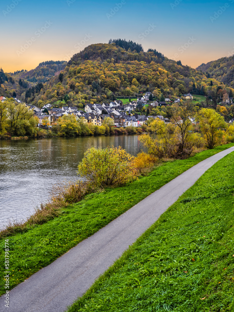 Sehl village with bright colour trees, pedestrian and cyclist pathway during autumn on Moselle river in Cochem-Zell district, Germany