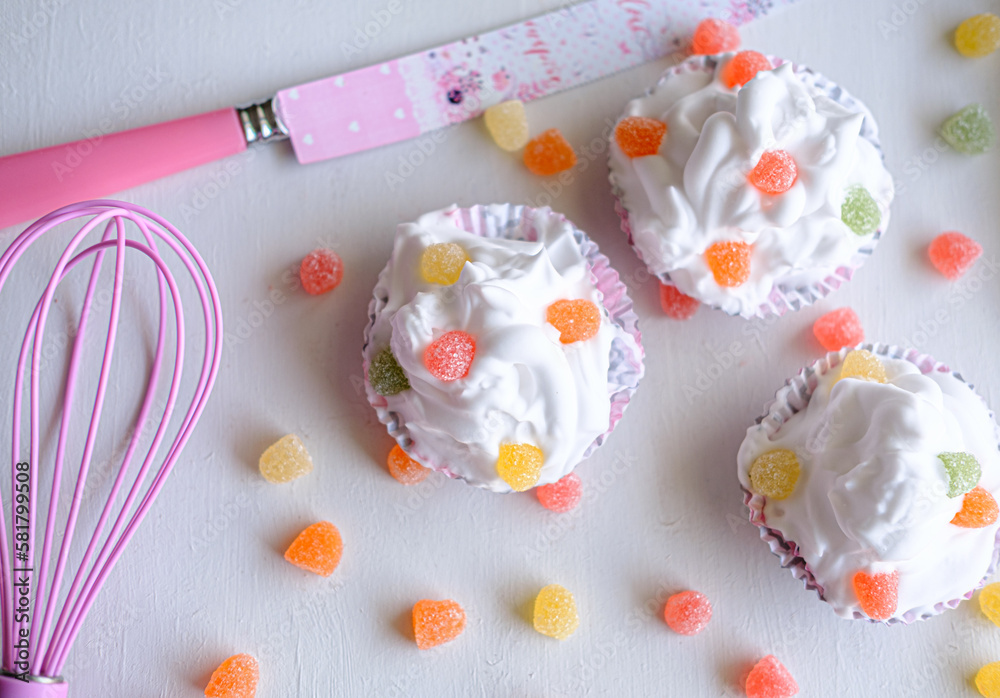 Three cupcakes with jelly beans on bright white background. Cupcakes with knife and orange, red, pink jellybeans for festive. Three cupcakes with jelly beans on bright white background. Cupcakes with knife and orange, red, pink jellybeans for festive.