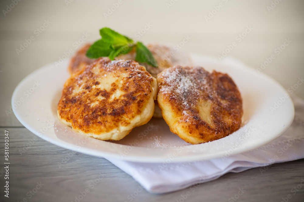 Sweet cooked cheesecakes in powdered sugar in a plate Sweet cooked cheesecakes in powdered sugar in a plate