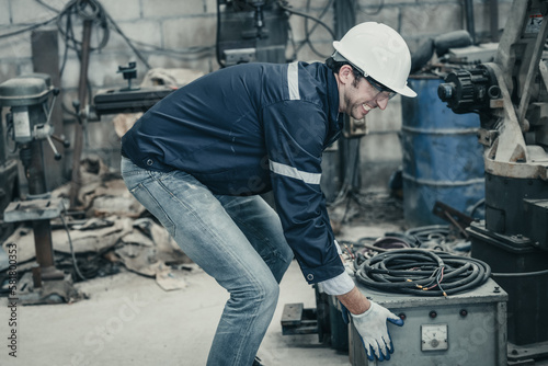 Foto The adult foreman suffered from a back injury while lifting and carrying heavy machinery and keeping a twisted posture