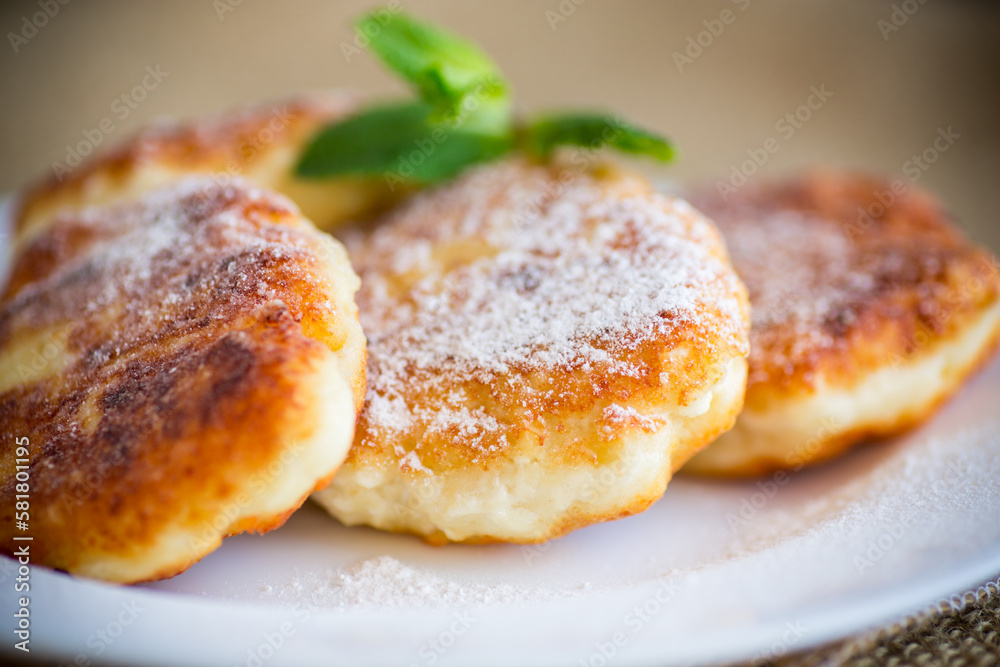 Sweet cooked cheesecakes in powdered sugar in a plate Sweet cooked cheesecakes in powdered sugar in a plate