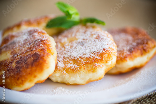 Sweet cooked cheesecakes in powdered sugar in a plate