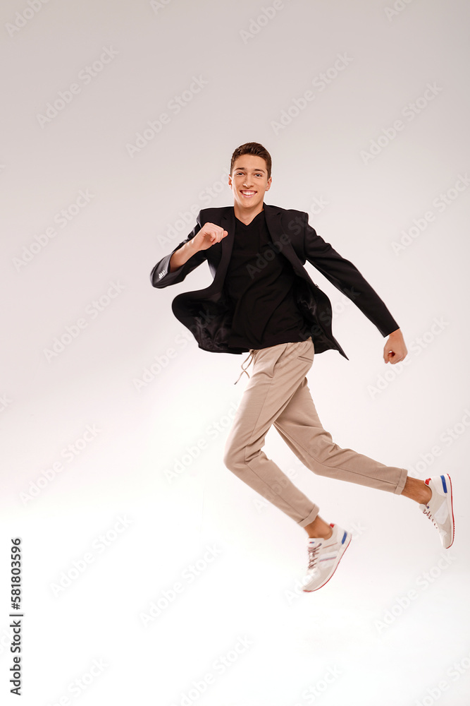 Crazy young man in casual clothes jumping over studio background with big smile on his face. People success concept.