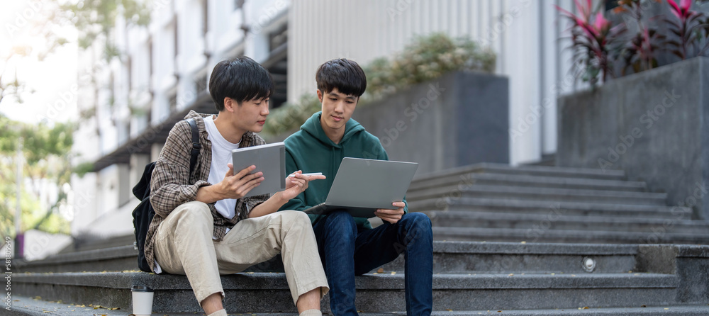 Happy Asian man college student playing mobile game on his smartphone with his friend