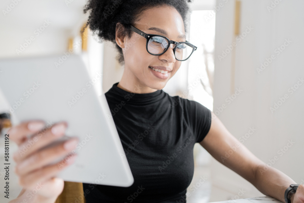 A young woman with glasses working at a workplace in an office, using a computer and tablet, coworking space. Freelancer student of the online project website. A young woman with glasses working at a workplace in an office, using a computer and tablet, coworking space. Freelancer student of the online project website.