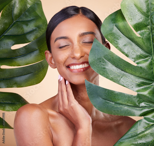 Woman, face and smile with leaf for natural skincare cosmetics, self love and care against studio background. Happy female beauty holding leafy green organic plant in sustainable eco facial treatment photo