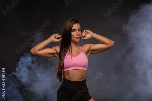 Sexy woman in sportswear posing. Young woman on a black background with smoke. Isolate