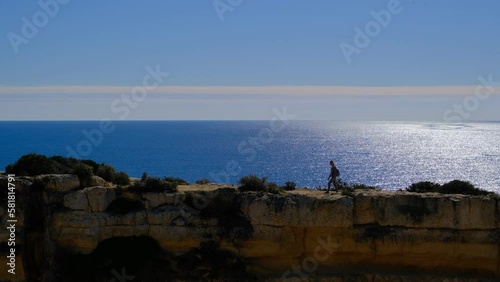 A woman on the top of cliffs at Marinha Beach in Algarve, Portugal
