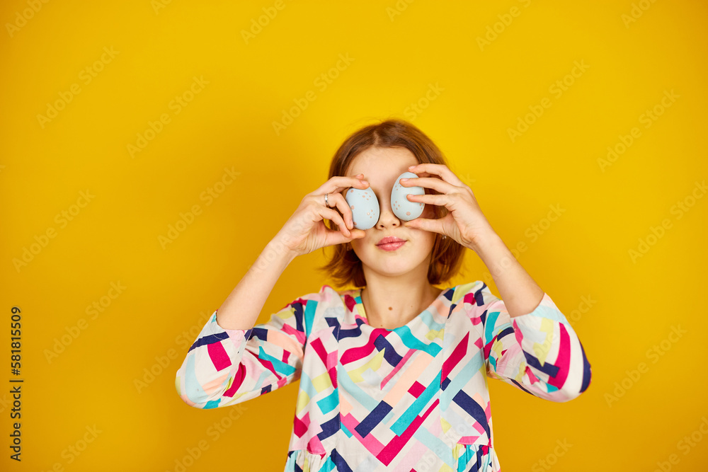 Happy playful teenager girl holding painted Easter eggs covering eyes Happy playful teenager girl holding painted Easter eggs covering eyes
