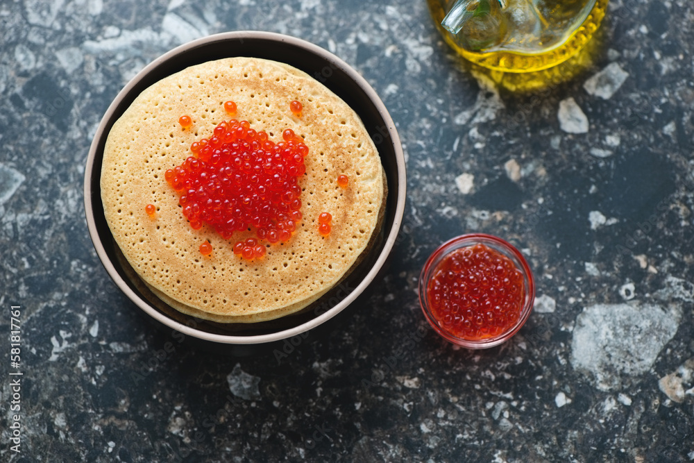 Bowl of pancakes with red caviar, horizontal shot on a dark-brown granite background, high angle view Bowl of pancakes with red caviar, horizontal shot on a dark-brown granite background, high angle view