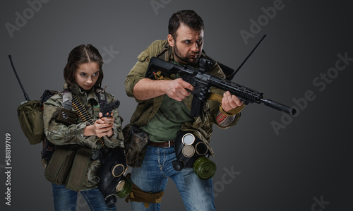 Portrait of post apocalyptic girl teenager and guy with guns against grey background.