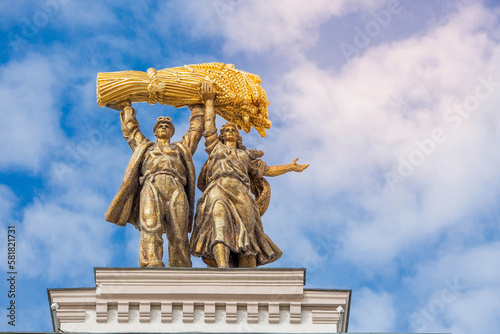 Close-up. Sculpture against the blue sky on the roof of the arch of the main entrance of the VDNH "Tractor driver and collective farmer" after restoration. Russia, Moscow, VDNH.