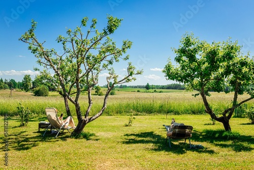 Two people relaxing in sun loungers under trees in the shade