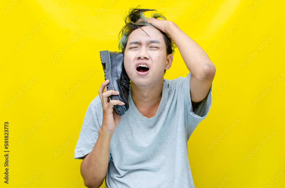 asian man acting and gesturing as a crazy, stupid, and dump person. asian man pretends to have a phone call using a shoe. asian man acting and gesturing as a crazy, stupid, and dump person. asian man pretends to have a phone call using a shoe.