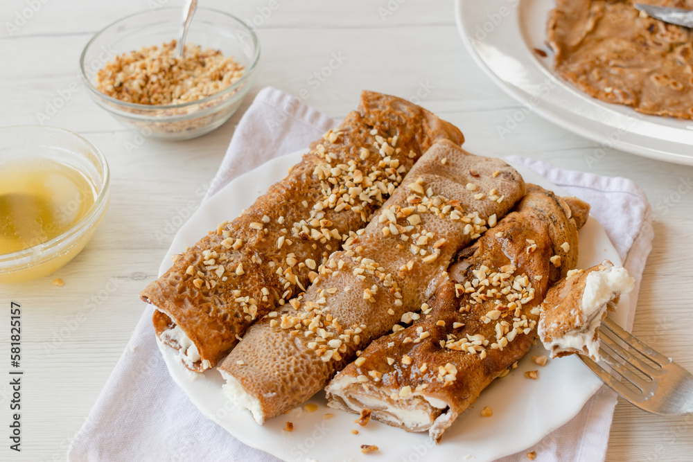 Tuscan Necci, chestnut flour crêpes filled with ricotta cream and topped with honey and chopped hazelnuts, traditional Italian recipe Tuscan Necci, chestnut flour crêpes filled with ricotta cream and topped with honey and chopped hazelnuts, traditional Italian recipe