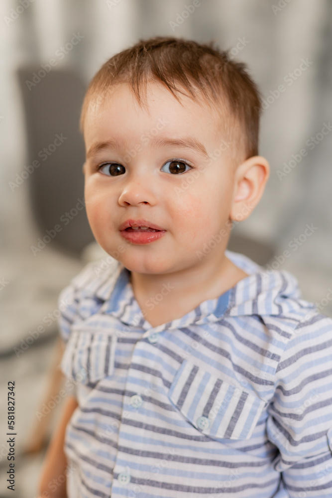 cute baby boy in jeans and shirt on a gray background in the studio