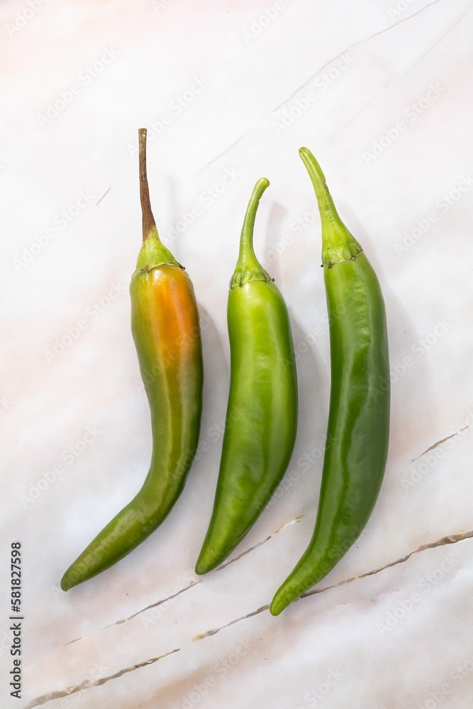Closeup of fresh jalapeno peppers on a white table Closeup of fresh jalapeno peppers on a white table