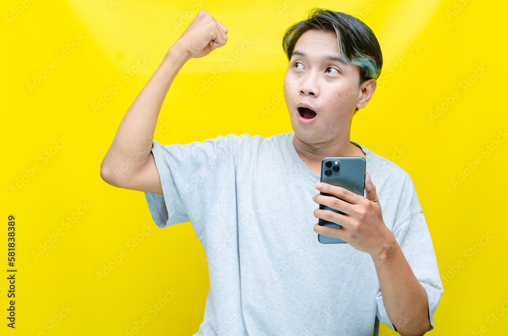 a shocked Asian man in peek-a-boo hair holding the phone and receiving good news. ecstatic A young, handsome Asian man being surprised after reading message on his smartphone. a shocked Asian man in peek-a-boo hair holding the phone and receiving good news. ecstatic A young, handsome Asian man being surprised after reading message on his smartphone.