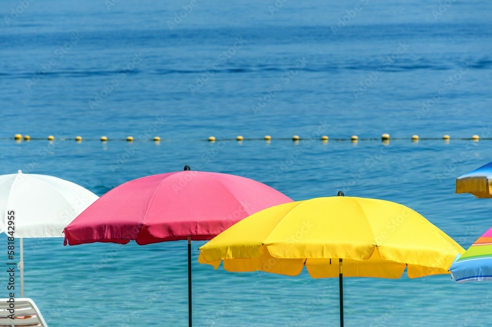 Selective focus shot of colorful umbrellas against the blue sea