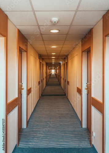 Empty hotel hallway with wooden doors © Marko Klarić/Wirestock Creators