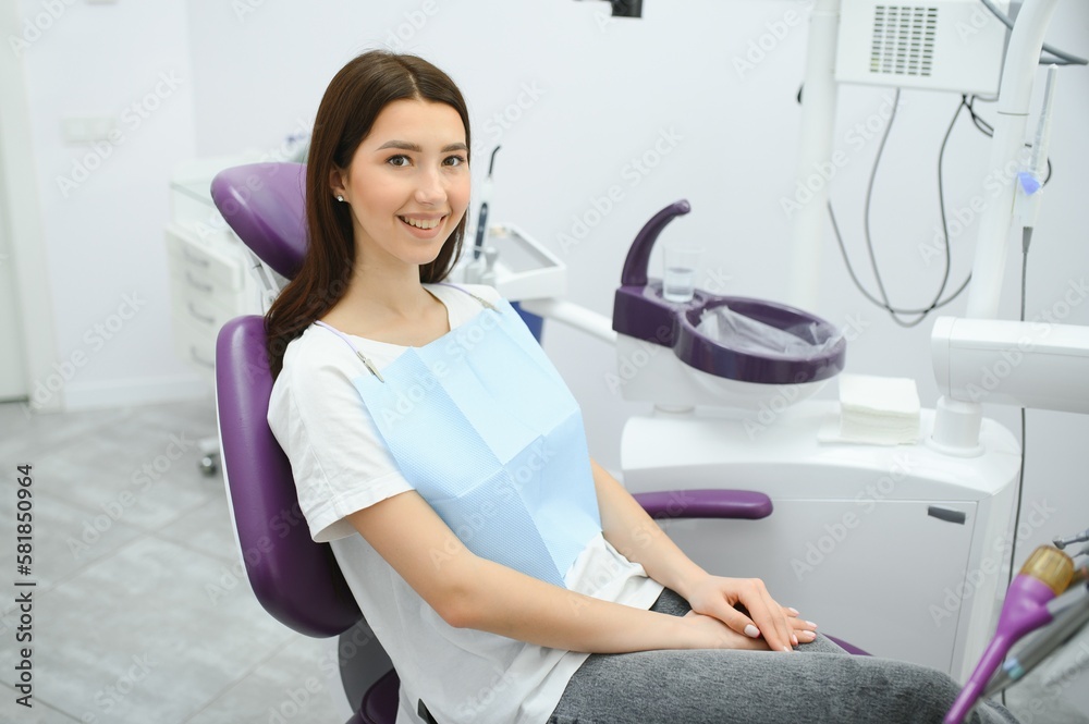 Portrait of a woman with toothy smile sitting at the dental chair at the dental office
