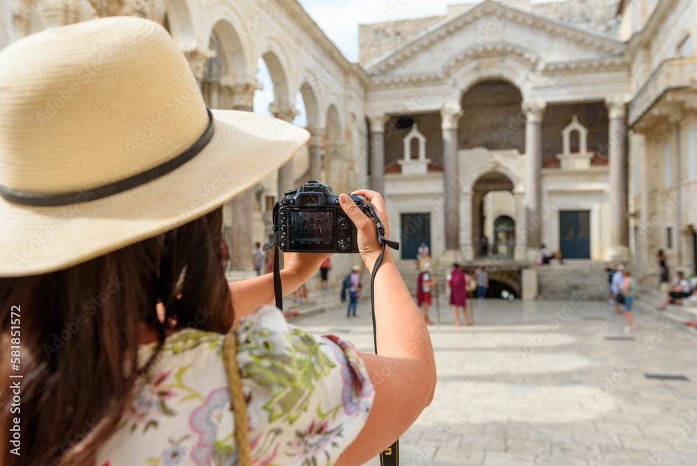 Woman holding camera taking a photo in city square at Diocletian's palace in Split, Croatia