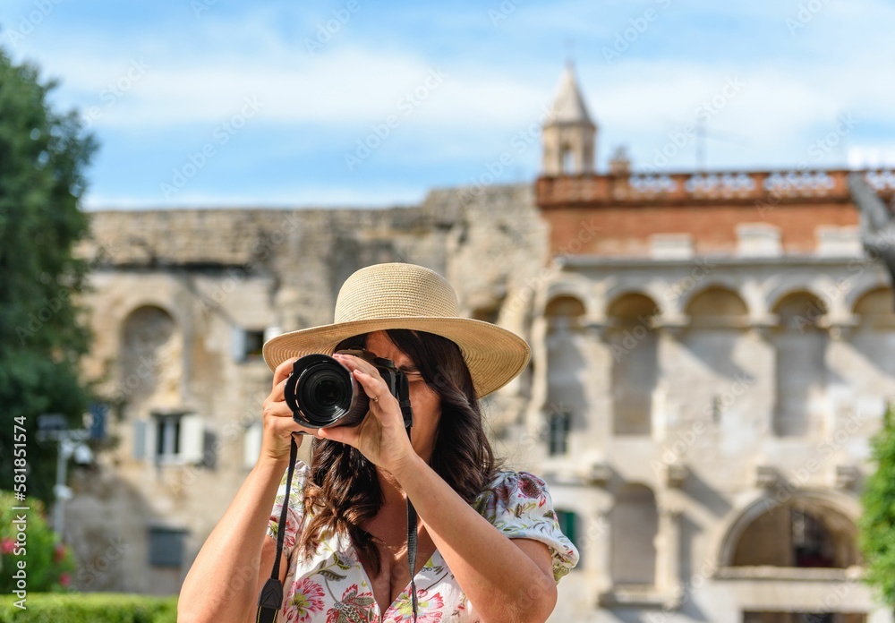 Woman with hat holding a camera taking pictures at Diocletian's palace in Split, Croatia