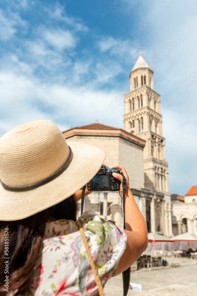 Woman in a sun hat holding up camera taking picture of a cathedral in Split, Croatia